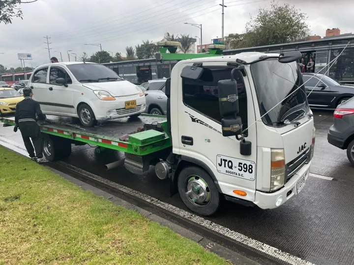 Grúa con carro blanco en vía principal