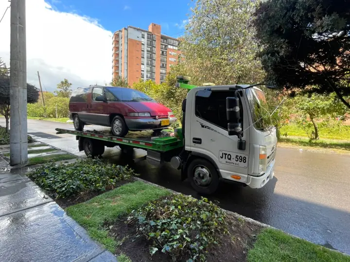 Grúa transportando un carro rojo