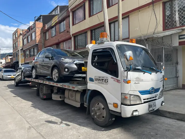 Grúa transportando una camioneta en barrio de Bogotá