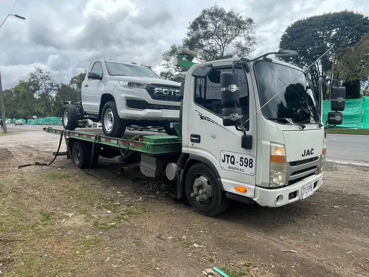 Grúa JAC transportando una camioneta blanca en Bogotá